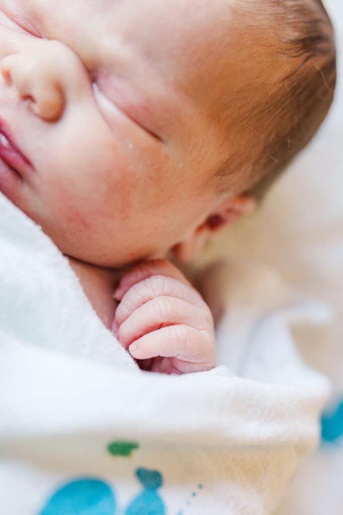 Raleigh Fresh 48 photographer capturing newborn baby stretching in hospital swaddle