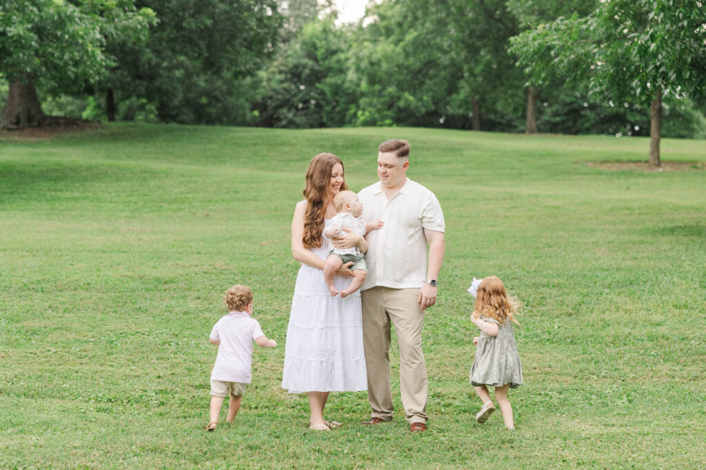 Two kids running around their mom who is wearing a white dress during their Raleigh Spring family photos