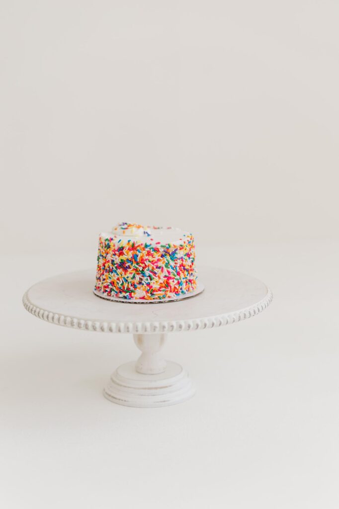 Simple white cake with sprinkles on cake stand prepared for first birthday cake smash session | Raleigh cake smash photographer