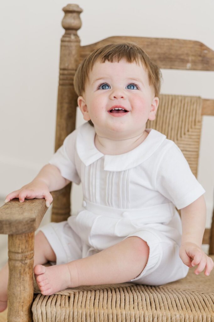 One year old baby sitting in wooden chair for milestone personality portraits before cake smash | Raleigh cake smash photographer