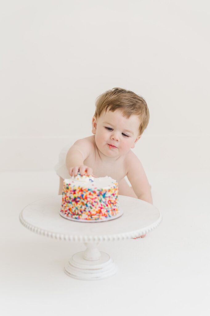One year old baby exploring sprinkle cake during first birthday cake smash session | Raleigh cake smash photographer