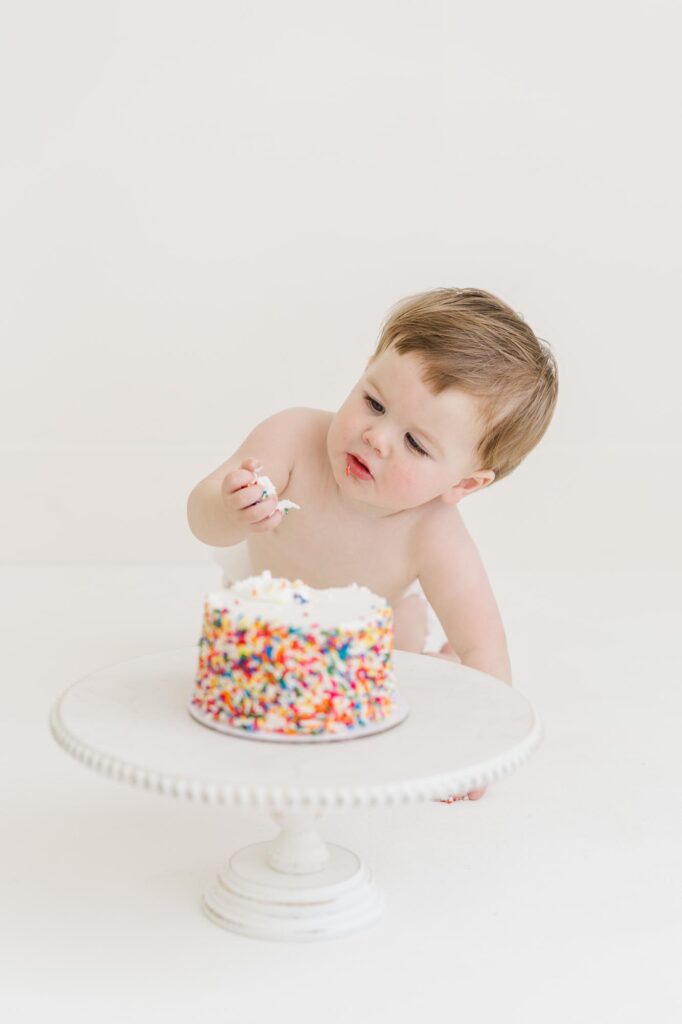One year old baby smashing sprinkle cake during first birthday cake smash session | Raleigh cake smash photographer