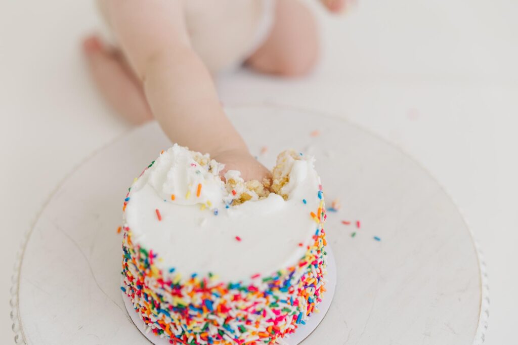 Baby's hand smashing a cake during their one year raleigh cake smash photographer session
