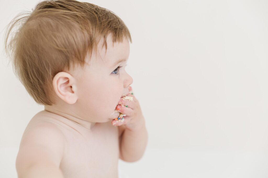 Close up of one year old baby eating cake during first birthday cake smash session | Raleigh cake smash photographer