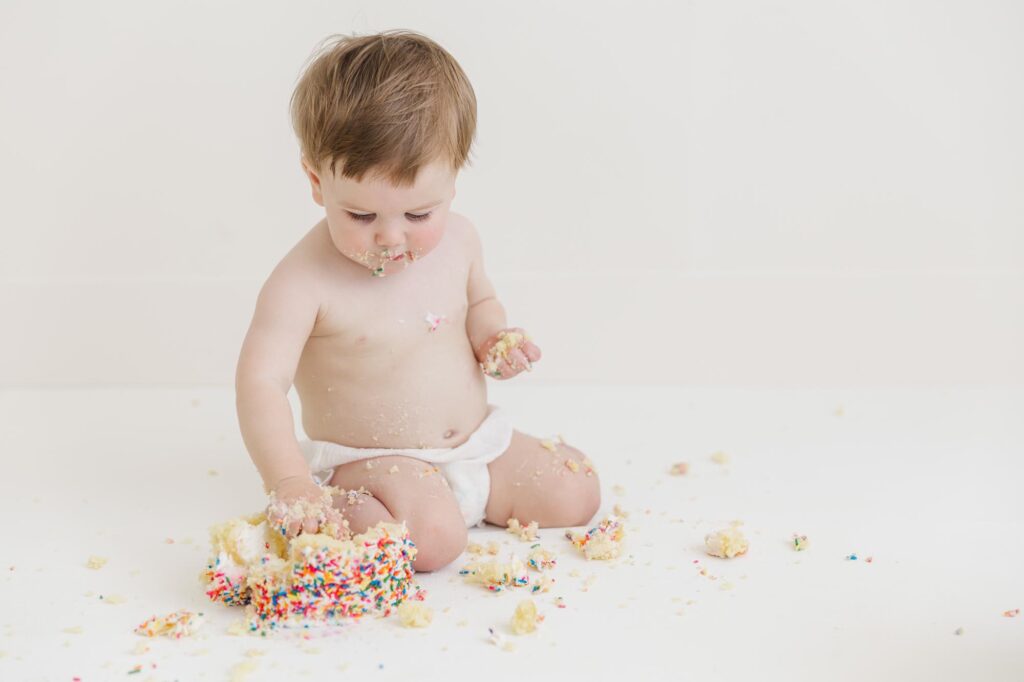 Baby exploring birthday cake during studio cake smash photography session in Smithfield near Raleigh