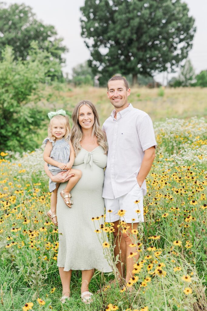 Family standing in a field of wildflowers during a summer session at one of the most colorful Raleigh photography locations.