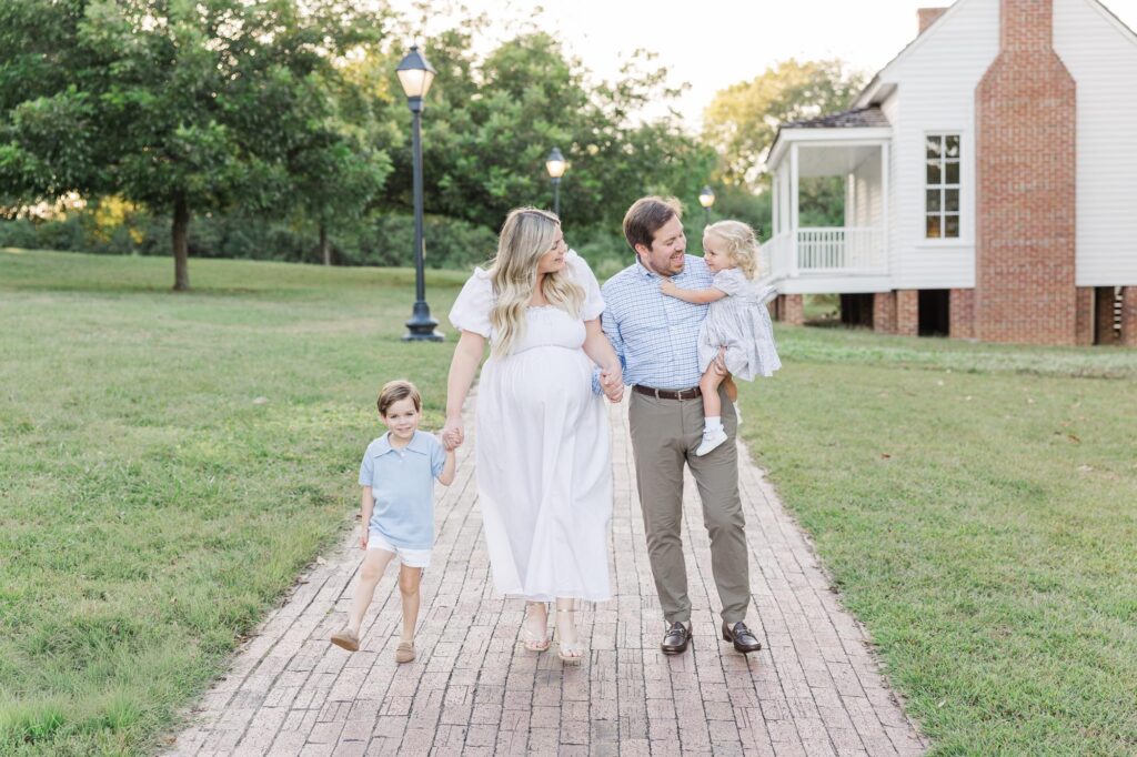 Young family walking down a brick path during a spring family photo session at Historic Oak View County Park, a popular Raleigh photography location.