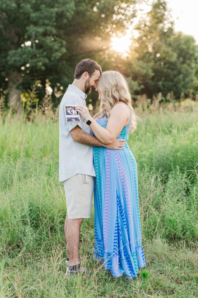 maternity photo of couple in grassy field during Raleigh spring mini sessions