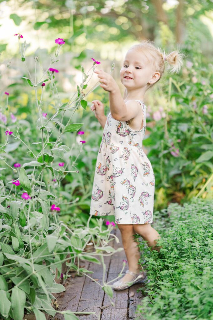 Young child exploring flowers during a spring family session at Historic Oak View County Park, a charming Raleigh photography location.