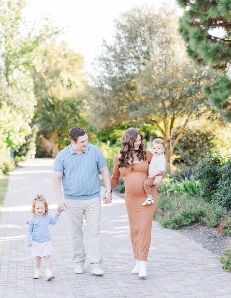 Family walking together along a garden path during a maternity session at one of the most beautiful Raleigh photography locations.