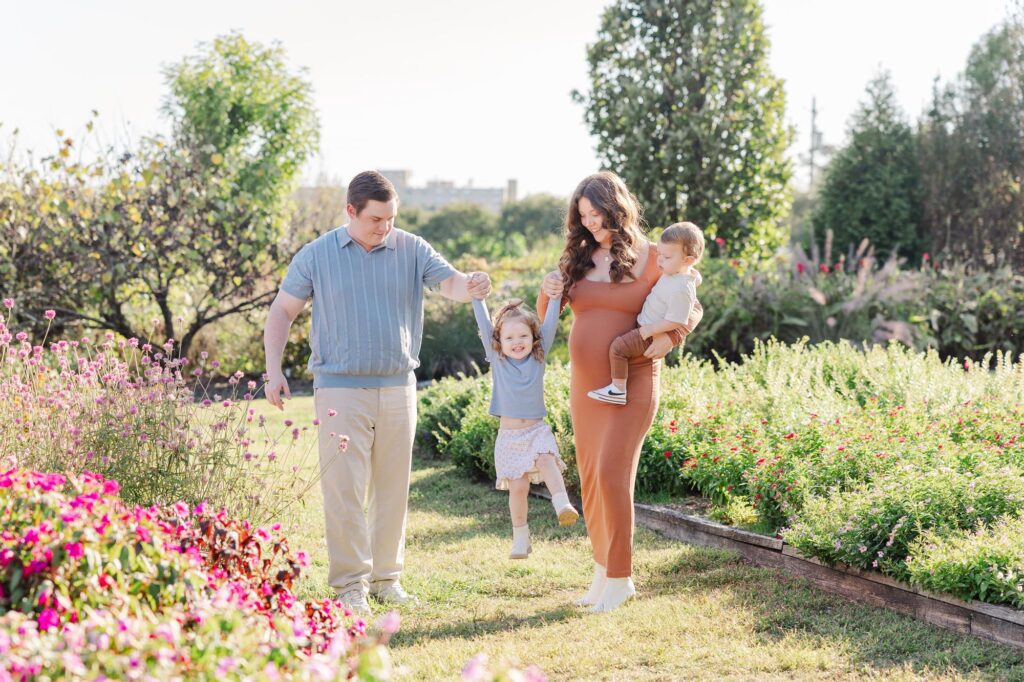 Parents swinging their little girl in a flower field at a Raleigh photography location. 