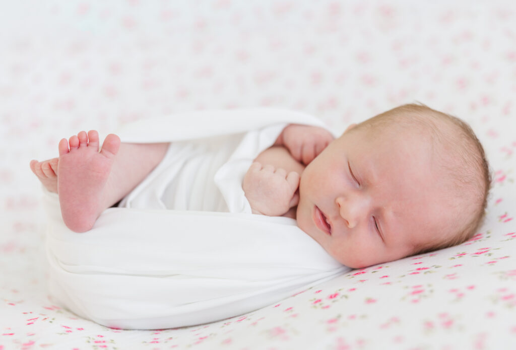 newborn baby laying on pink floral backdrop in raleigh newborn studio