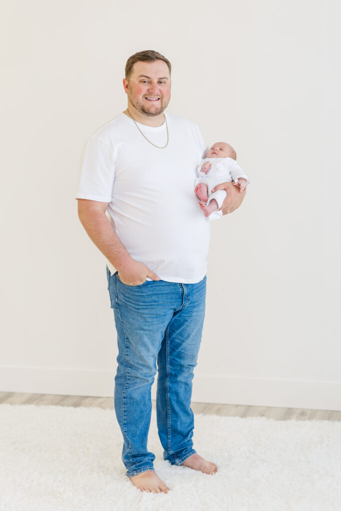 dad in white shirt and jeans holding newborn baby