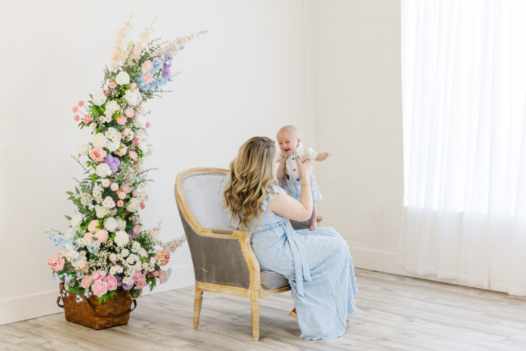 Mother and son smiling at each other in front of spring colored flowers during their mother's day minis raleigh nc 